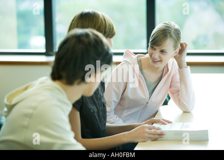 Tre studenti seduti a tavola, chat Foto Stock