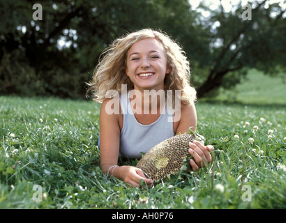 Donna sdraiata su erba con sorridente girasole Foto Stock