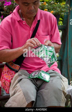 L'uomo vestito di rosa, un artigiano a, il Doi Suthep Chiang Mai Thailandia. Uomo asiatico rendendo riutilizzato lattine di metallo curiosità turistiche o negozio di souvenir Foto Stock