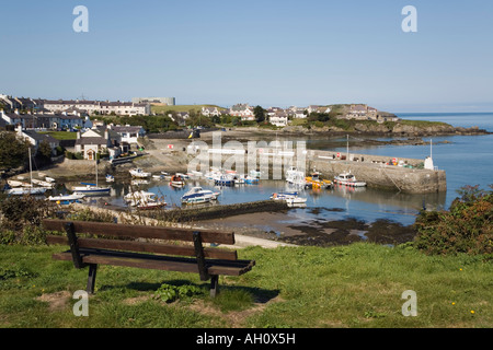 Sedile unico con vista sul porto di barche nel pittoresco più settentrionale del villaggio gallese di Cemaes, Isola di Anglesey, Galles del Nord, Regno Unito Foto Stock