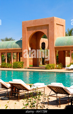 Il Marocco , Marrakesch , esclusivo Hotel Amanjena , area piscina con sedie a sdraio & esotici moderna architettura tradizionale Foto Stock