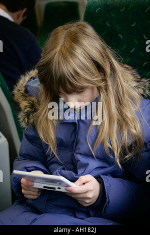 Giovane ragazza che gioca con il Nintendo DS Lite Giochi portatili console in un treno, England, Regno Unito Foto Stock