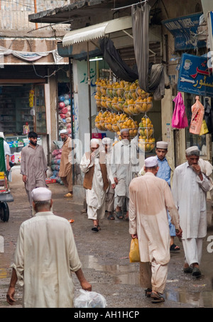 Gli uomini in shalwar kameez a piedi attraverso il vecchio bazar di Peshawar Pakistan Foto Stock