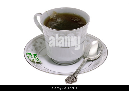 Tè nero con un sacchetto da tè in bianco tazza da tè piattino cucchiaino stagliano su sfondo bianco Foto Stock
