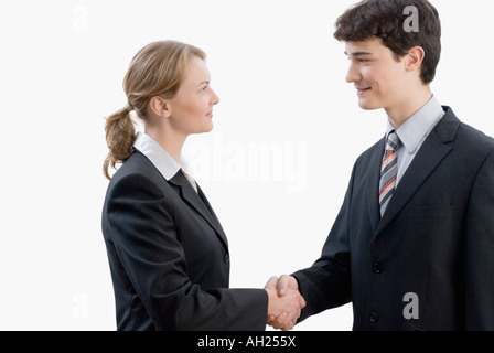 Profilo laterale di una imprenditrice stringono le mani con un imprenditore e sorridente Foto Stock