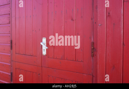 Close up dettaglio di colore rosso brillante colorati porta di legno su una malga o un capannone o chiosco o stand in alluminio con maniglia della porta Foto Stock