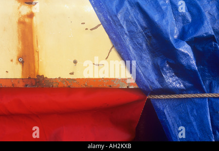 Dettaglio della parte di macchinari protetti dagli elementi da rosso e blu in plastica o nylon telone fogli Foto Stock