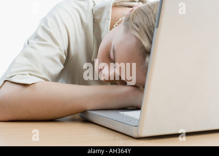 Close-up di una giovane donna che dorme nella parte anteriore di un laptop Foto Stock