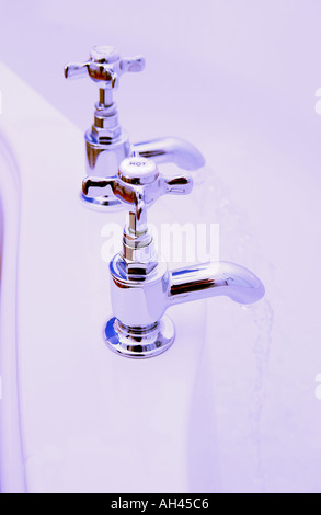 Primo piano dei rubinetti cromati che corrono l'acqua nel bagno Foto Stock