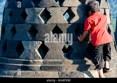 Giovane indonesiano ragazzo arriva a toccare le mani di Buddha per buona fortuna Borobudur Indonesia Foto Stock