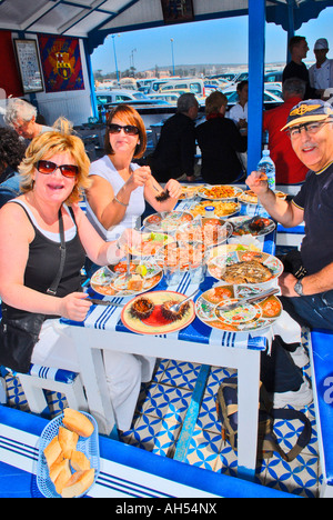 Essaouira , Place Moulay Hassan , tipico African quayside scena del tradizionale ristorante di frutti di mare con i mangiatori di felice in aria aperta Foto Stock