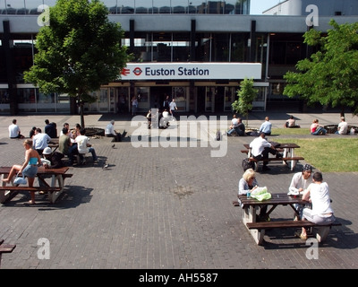 London Euston Terminus stazione ferroviaria piazzale con persone passeggeri in giornata di sole tavoli picnic all'aperto Camden Inghilterra UK Foto Stock