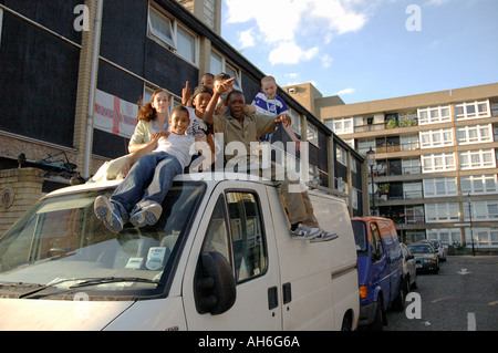 Gruppo vivace dei bambini di arrampicata e saltare sul furgone parcheggiato sul loro alloggiamento estate in Kensal Green West London. Foto Stock