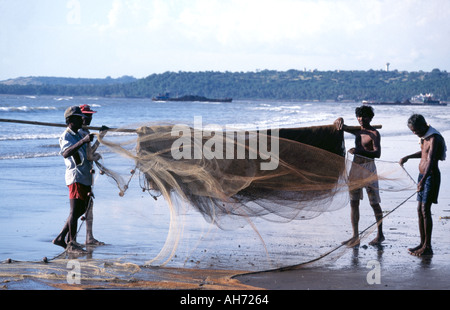 I pescatori che trasportano le loro reti da pesca sulla spiaggia di Goa in India meridionale. Foto Stock