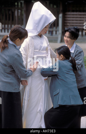 Tre assistenti irritabilità con la sposa di kimono bianco indossato durante una cerimonia di nozze tradizionale Foto Stock