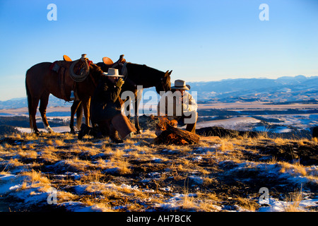 Due uomini inginocchiato a terra di fronte a un falò Foto Stock