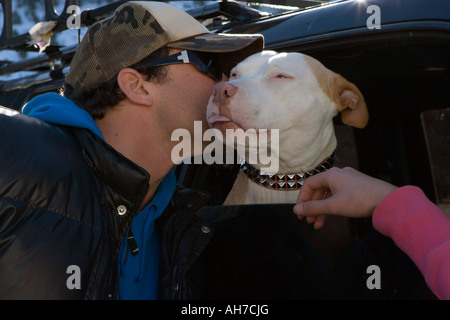 Close-up di una metà uomo adulto baciando un cane in uno sport utility vehicle Foto Stock