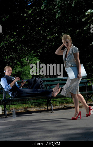 Imprenditrice a piedi con un imprenditore sdraiata su una panchina nel parco Foto Stock