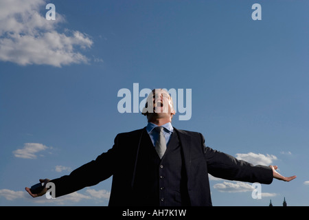 Basso angolo di visione di un imprenditore gridando con braccia aperte Foto Stock
