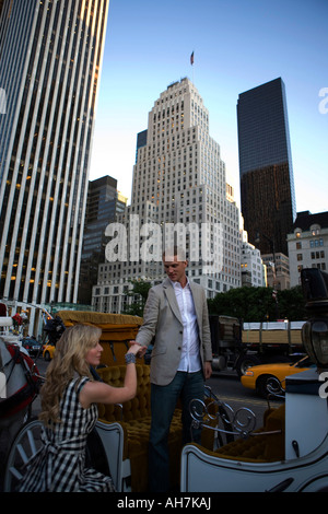 Giovane uomo aiuta una giovane donna a bordo di un carro horsedrawn, Central Park, Manhattan, New York, New York, Stati Uniti d'America Foto Stock