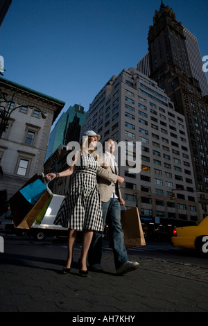 Basso angolo vista di una giovane coppia di camminare sulla strada, la città di New York, New York, Stati Uniti d'America Foto Stock
