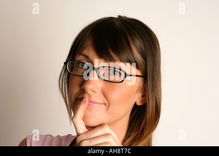 Giovane donna che indossa occhiali con un espressione pensosa Foto Stock