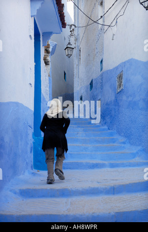 Giovane donna musulmana fino a piedi vicolo a gradini Chefchaouen Marocco Africa del Nord Foto Stock