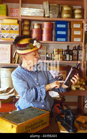 WISCONSIN Old World Wisconsin Eagle Thomas General Store interior donna in costume esaminare bottiglia Foto Stock