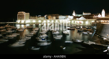 Barche di bob durante la notte in acqua nel porto di Dubrovnik illuminato dalle luci della città sulla costa mediterranea della Croazia Foto Stock