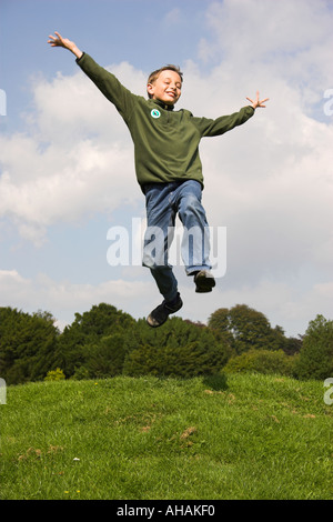 Dieci anni di old boy jumping braccia ampia. Foto Stock