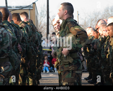 Soldati in uscita per la distribuzione in Iraq a prepararsi per la preghiera come bambina guarda con le mani incrociate USA Foto Stock