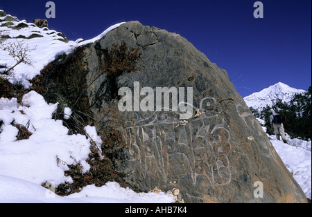 Una fede viva mantra o sacra sillabe essendo dipinta su un masso sul ciglio della strada al villaggio Ngawal Area Annapurna Nepal Foto Stock