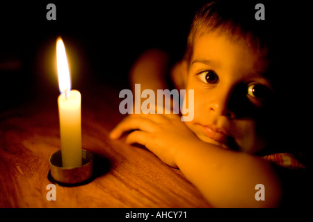 Testa e spalle ritratto di un bambino piccolo a lume di candela Foto Stock