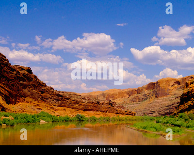 Il Green River aprendo tra rocce rosse scogliere di montagna, circondata dal verde lussureggiante fogliame shorline, sotto nuvoloso cielo blu Foto Stock