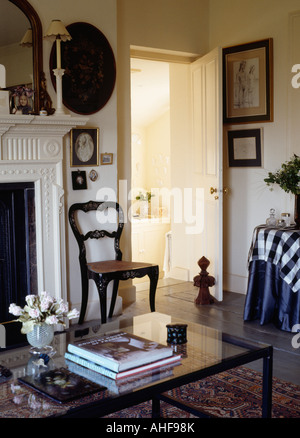 Sedia antica accanto a porta aperta in soggiorno con i libri sul tavolo da caffè Foto Stock
