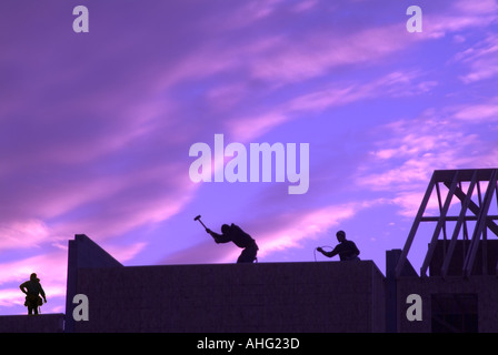 Lavoratori edili conciatetti sul tetto al tramonto Foto Stock