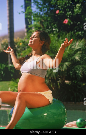 Incinta donna ispanica facendo esercizio di yoga all'aperto Foto Stock
