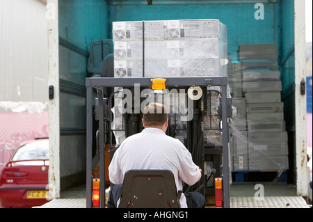Operai di coda di scarico del camion di sollevamento con carrello contenente pallet avvolti di pile di computer scatole di sistema Foto Stock