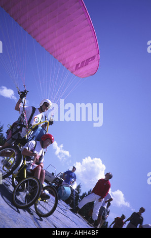 Pilota di parapendio di decollare con un passeggero disabile in un atto specialy carrozzella a Annecy nelle Alpi francesi Foto Stock