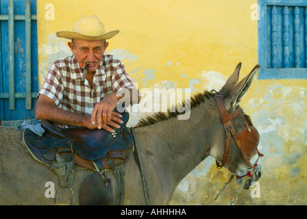 Caraibi Cuba Trinidad Ritratto di anziani uomo cubano di fumare un sigaro e appoggiato sulla sella del gretto asino Foto Stock