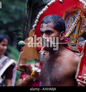 SINGAPORE Southeast Asia religione devoto maschio a Thaipusam festival indù. Aghi perforano la linguetta attraverso la guancia. Foto Stock