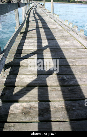 Ombre su una passerella di legno andando per mare Isola del Sud della Nuova Zelanda Foto Stock