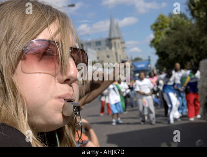 Ragazza al carnevale di Notting Hill soffia un fischio Foto Stock