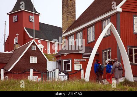 La gente a piedi attraverso i tradizionali whale jawbone arch ingresso al museo locale e chiesa a Sisimiut sulla costa ovest della Groenlandia Foto Stock