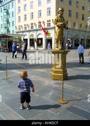 Bambino ammirando una statua umana sulla grande piazza Torgallmenningen nel centro di Bergen in Norvegia Foto Stock