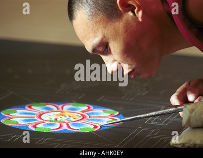 Monaco tibetano lavorando su un mandala murale di sabbia Foto Stock