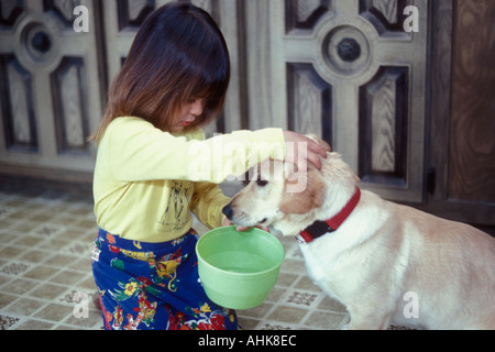 Bambino cercando di insegnare al cane a bere dalla ciotola Foto Stock