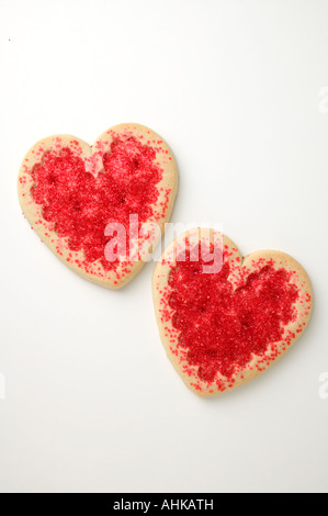 Due a forma di cuore i cookie di zucchero con un pizzico di colore rosso su sfondo bianco Foto Stock