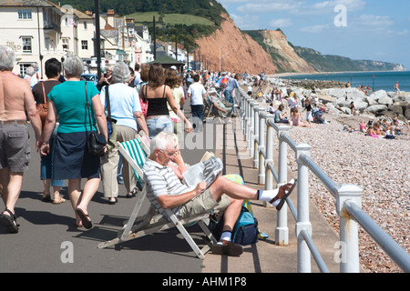 La gente che camminava lungo il mare di Sidmouth e seduti in sedie a sdraio Devon England Foto Stock