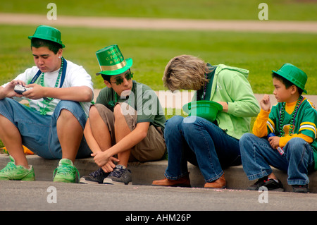 Famiglia caucasica con cappellini verdi seduta sul marciapiede a san Patrizio parata del giorno di San Diego California USA Foto Stock